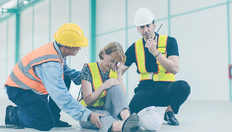 mujer en el suelo con las manos en la rodilla, ha sufrido un accidente laboral. Importante saber los procedimientos clave